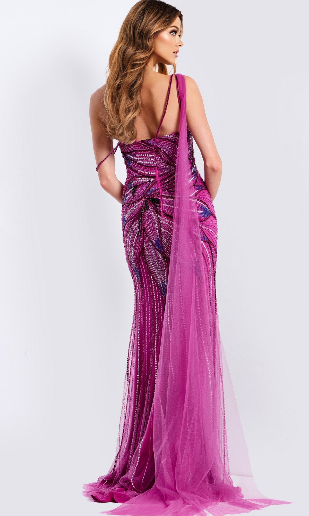 A woman poses against a plain, light background in the Jovani 45876—a long, beaded magenta prom dress featuring a backless design, fitted silhouette, sparkling embellishments, and a sheer train.